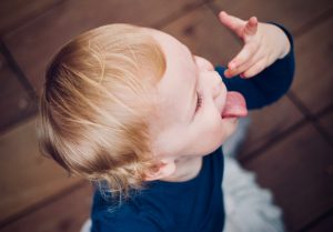 Bébé qui mange seul en tirant la langue