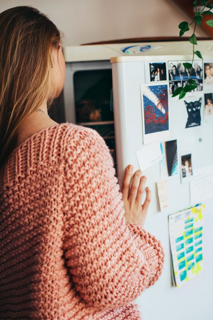 Une femme qui ouvre la porte de son frigo pour cuisiner